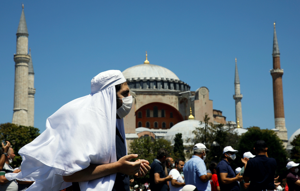 A man gestures as people wait for the beginning of Friday prayers outside Hagia Sophia Grand Mosque, for the first time after it was once again declared a mosque after 86 years, in Istanbul, Turkey, July 24, 2020. REUTERS/Umit Bektas
