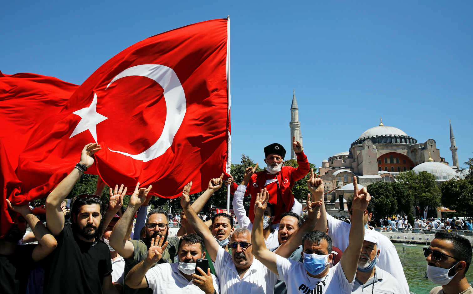People gesture as they wait for the beginning of Friday prayers outside Hagia Sophia Grand Mosque, for the first time after it was once again declared a mosque after 86 years, in Istanbul, Turkey, July 24, 2020. REUTERS/Umit Bektas
