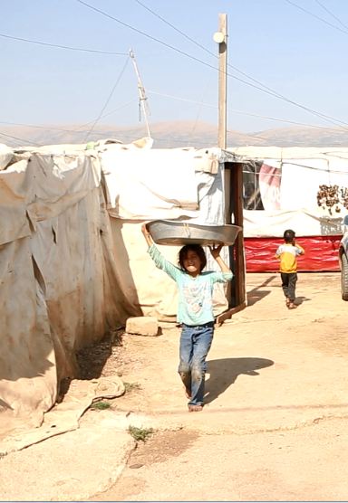 A child in the Gaza camp holds a washing dish over her head